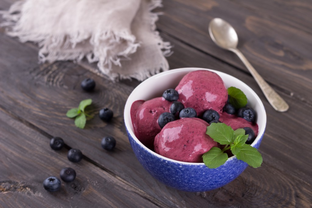 Blueberry ice cream with fresh blueberries and mint on a wooden table